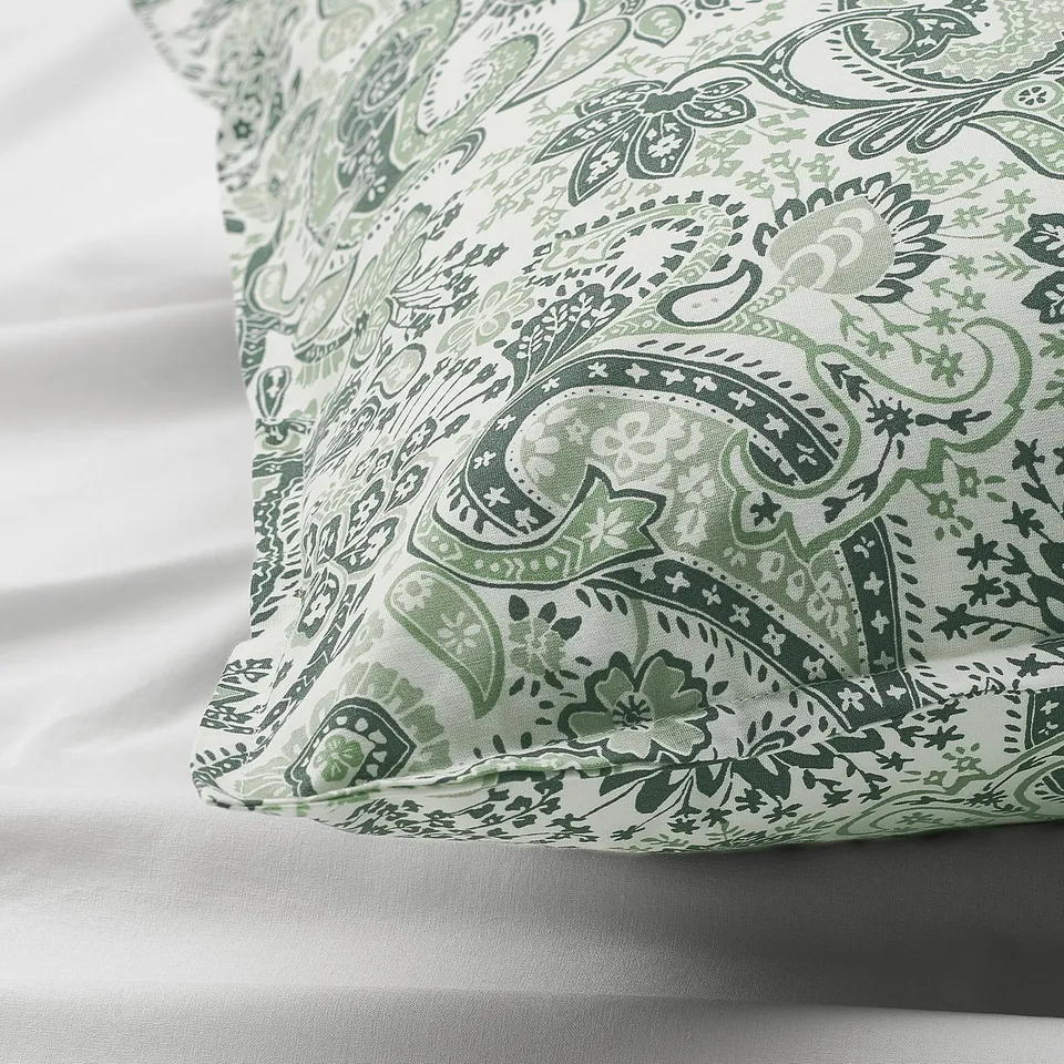 Green and white paisley pillowcase, intricate pattern, soft fabric blend, on smooth bedding.