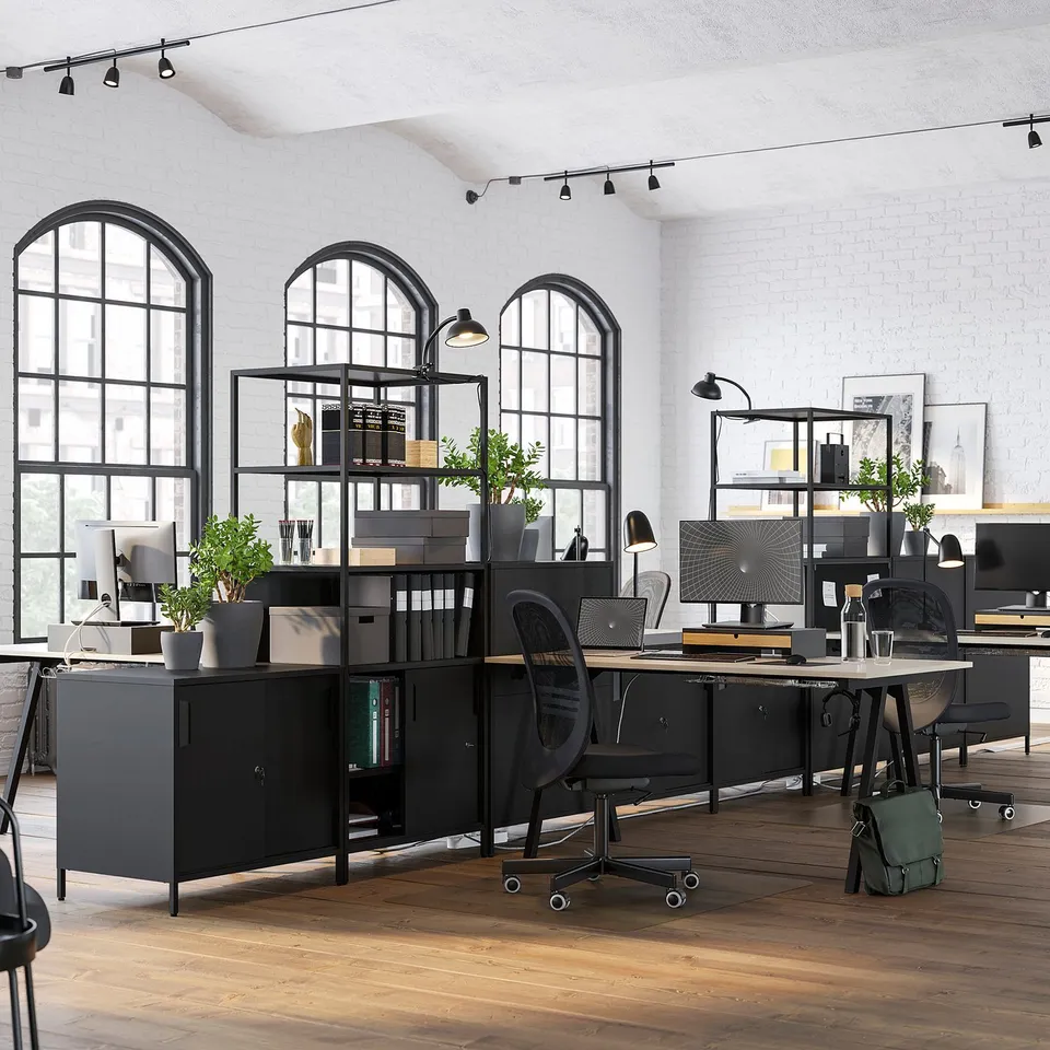 Modern office space with TROTTEN black metal double-sided storage cabinet, arched windows, and wooden floor.
