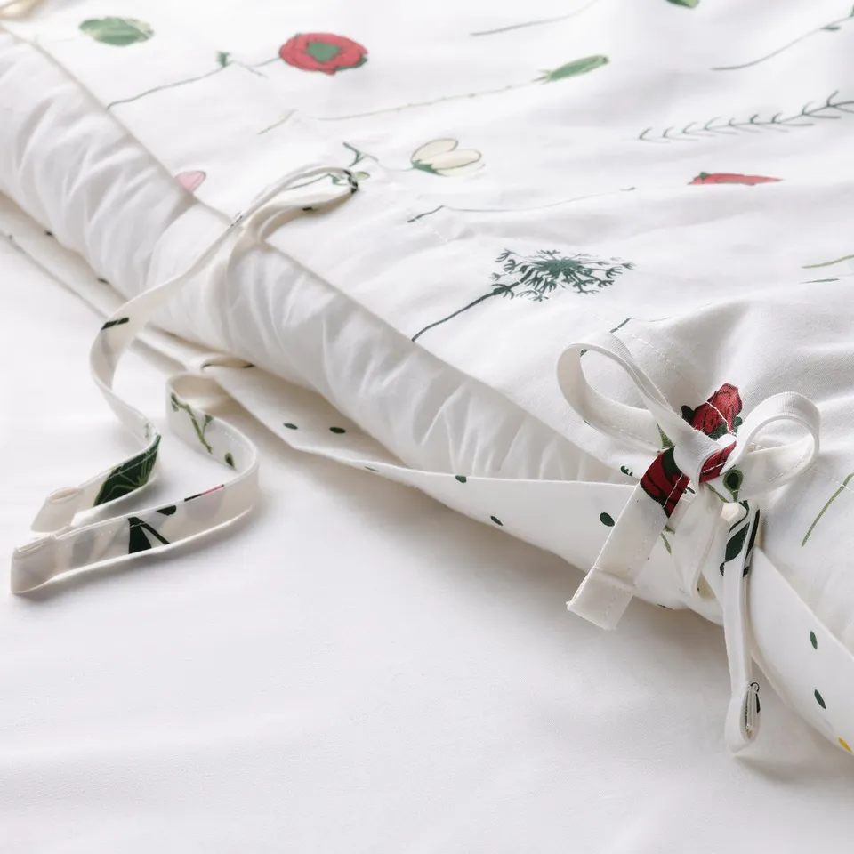 A rolled duvet cover with flower and dot patterns, tied with ribbon.