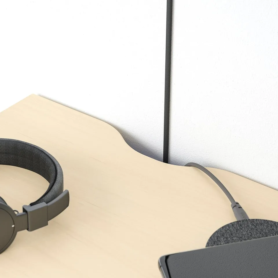 Headphones casually placed on a modern, minimalist beige bedside table with a sleek, grey metal edge.