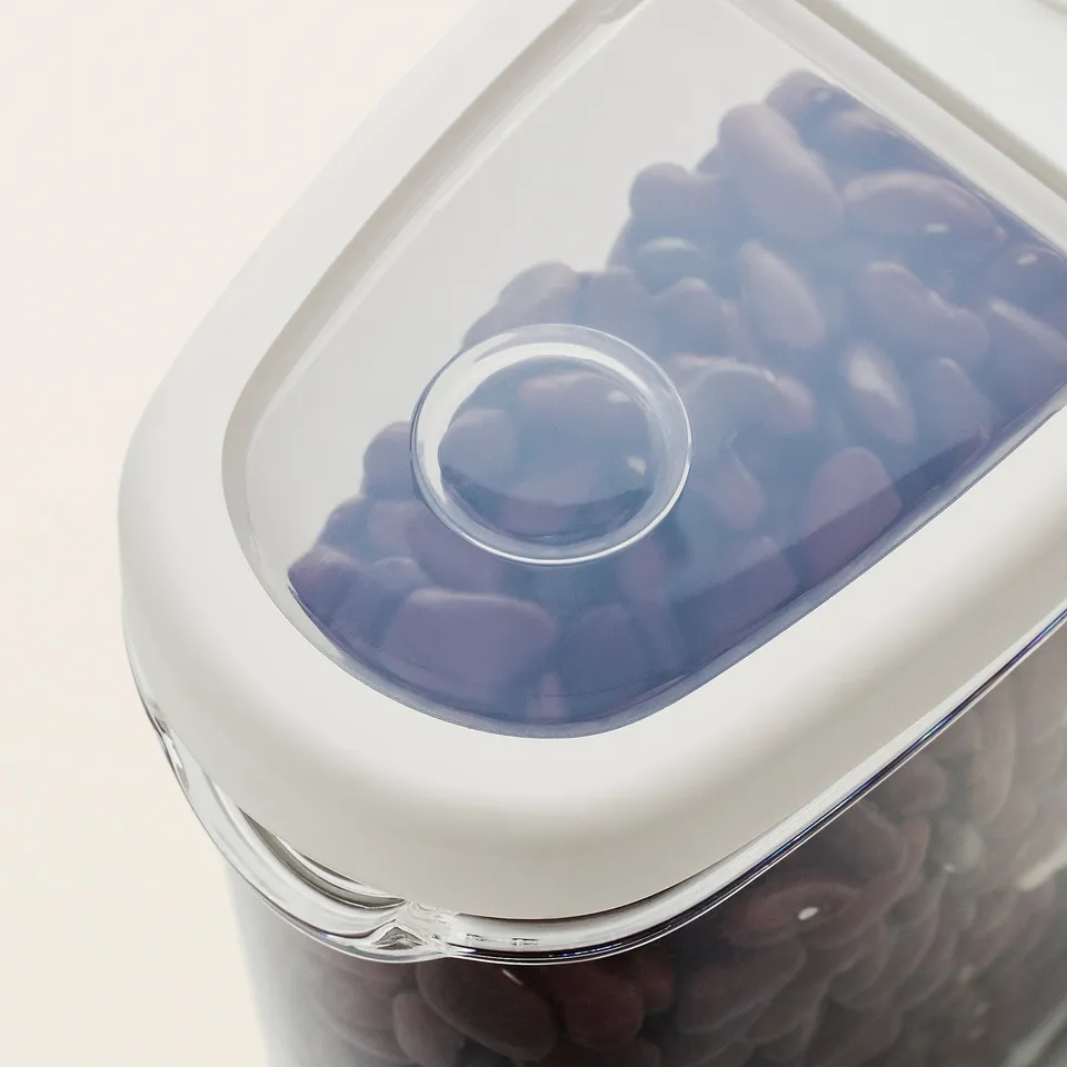 Clear plastic container with white lid, holding purple and dark items, designed for dry food storage.