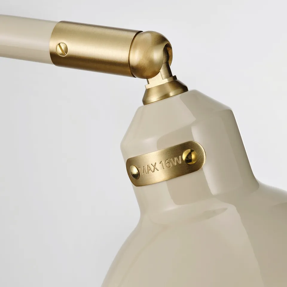 Close-up of elegant lamp joint. Gold-colored metal screws secure white, textured lamp base. Engraved label says max 16w.