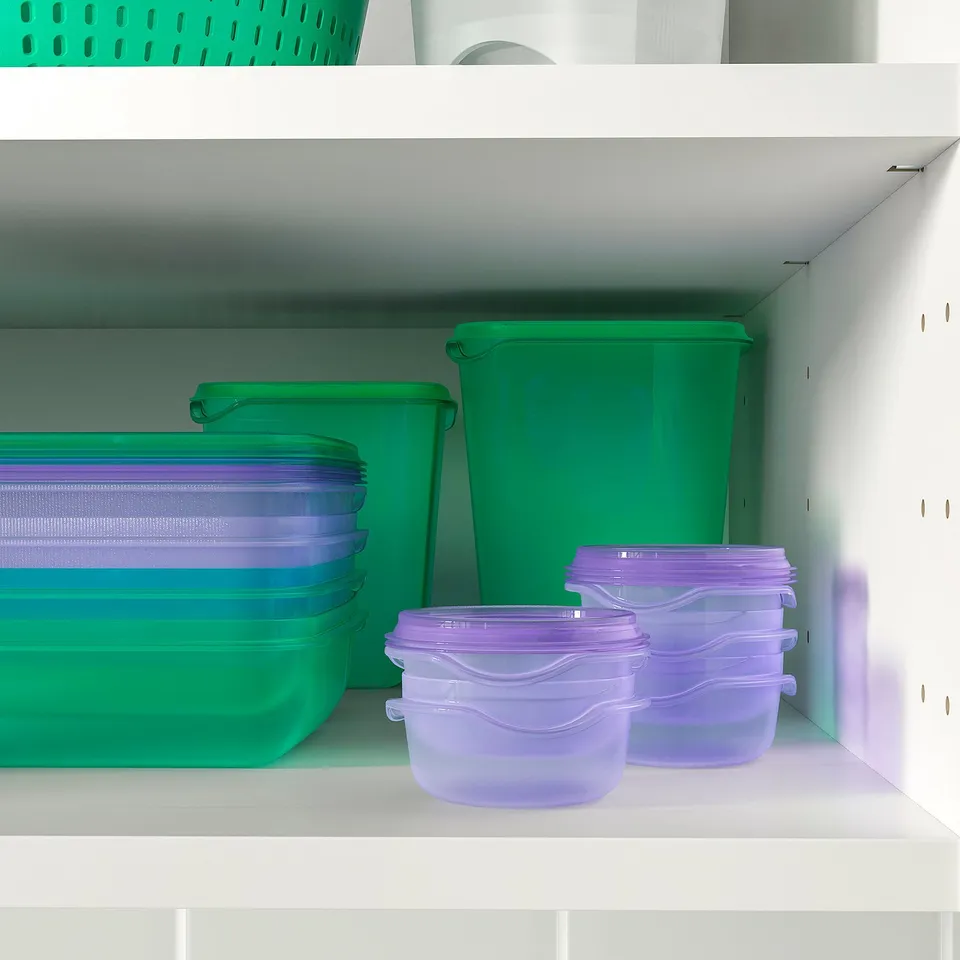 Shelf with various green and purple food storage containers, some stacked and some alone, showing organisational and space-saving functions.