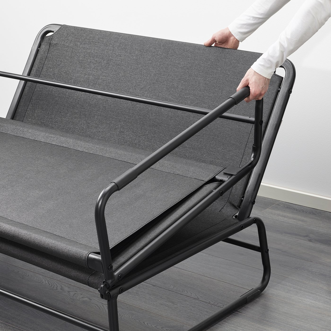 Image shows person adjusting HAMMARN sofa bed, demonstrating its quick transformation into a spacious bed.