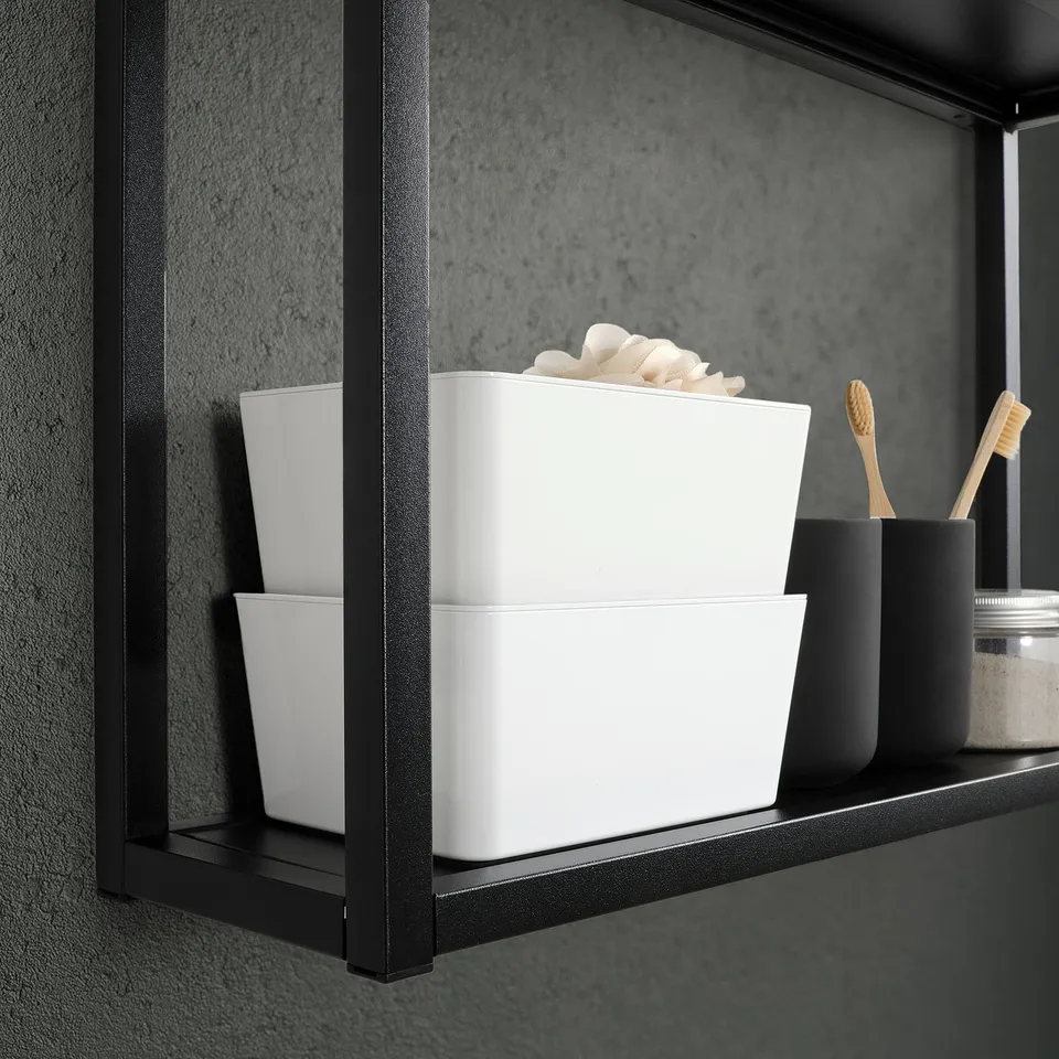 Black shelf with three white KUGGIS boxes, one stacked with toothbrushes, and another with white items. Provides organised storage for small items.