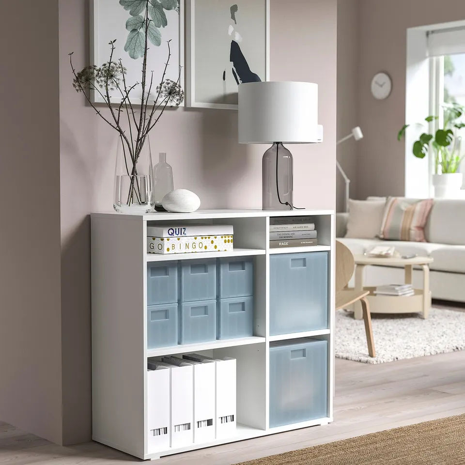 Modern living room with PANSARTAX storage unit, light blue boxes, lamp, and vase, near sofa.