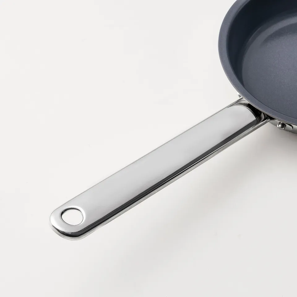 Stainless steel frying pan handle, securely attached to non-stick pan, showcasing durable construction and sleek design.