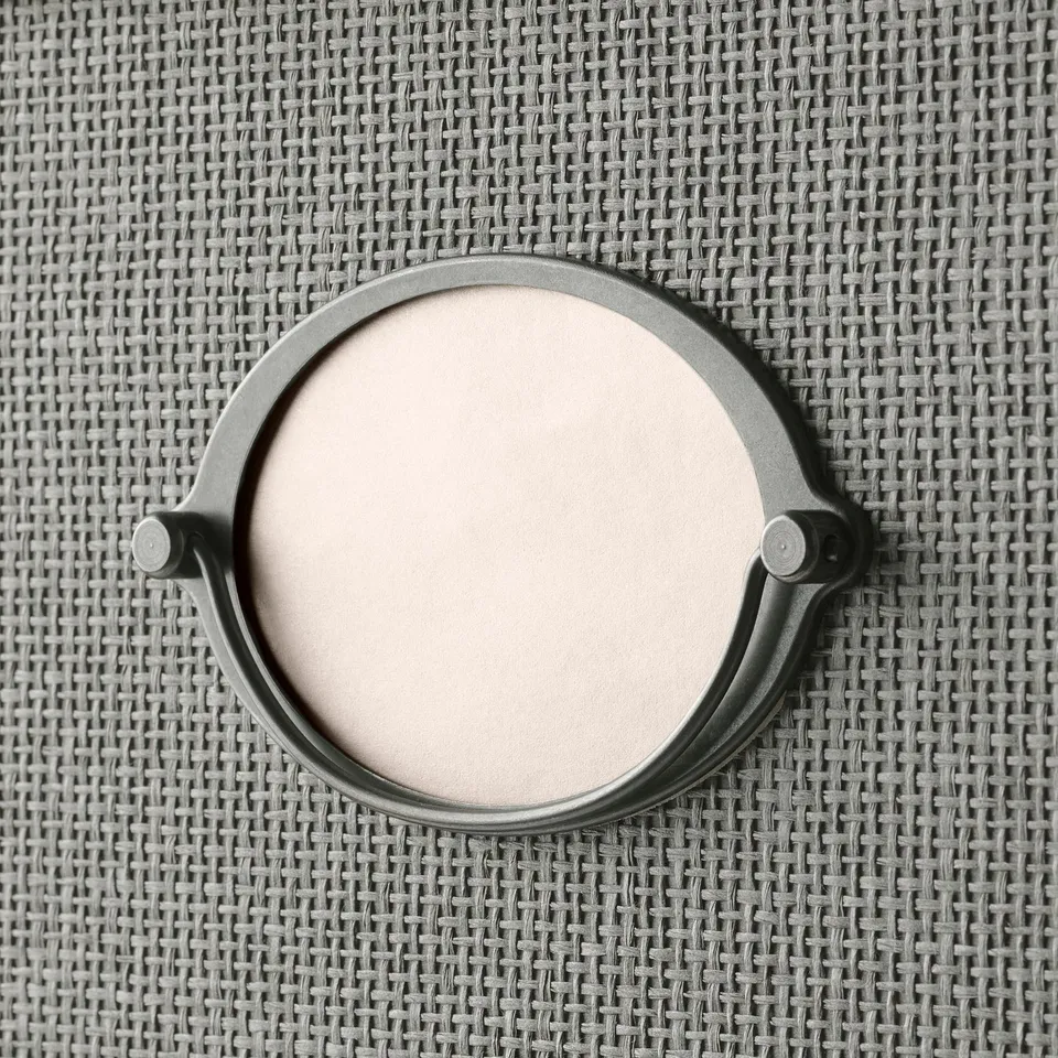 Circular metal object on woven paper, likely part of a stylish storage box.