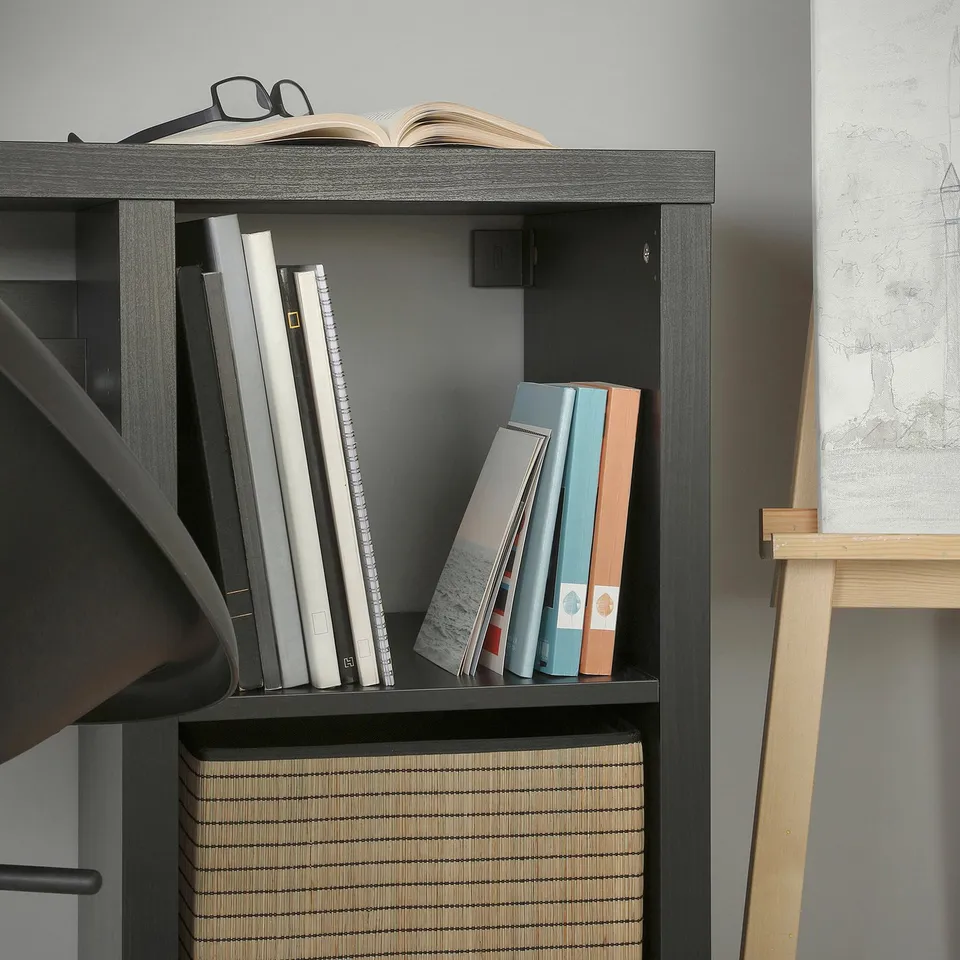 Modern black bookshelf with various books and a large artistic map to the side.