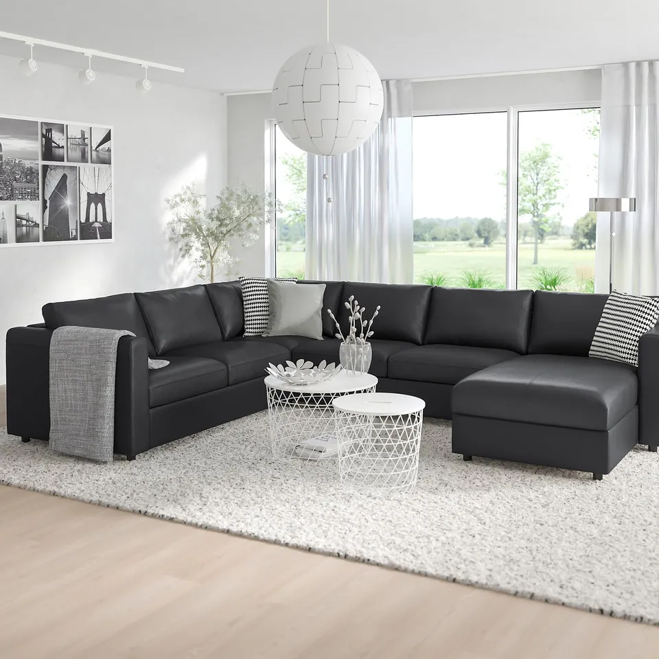 Modern black l-shaped VIMLE sofa in room with large window, white rug, and unique lamp.