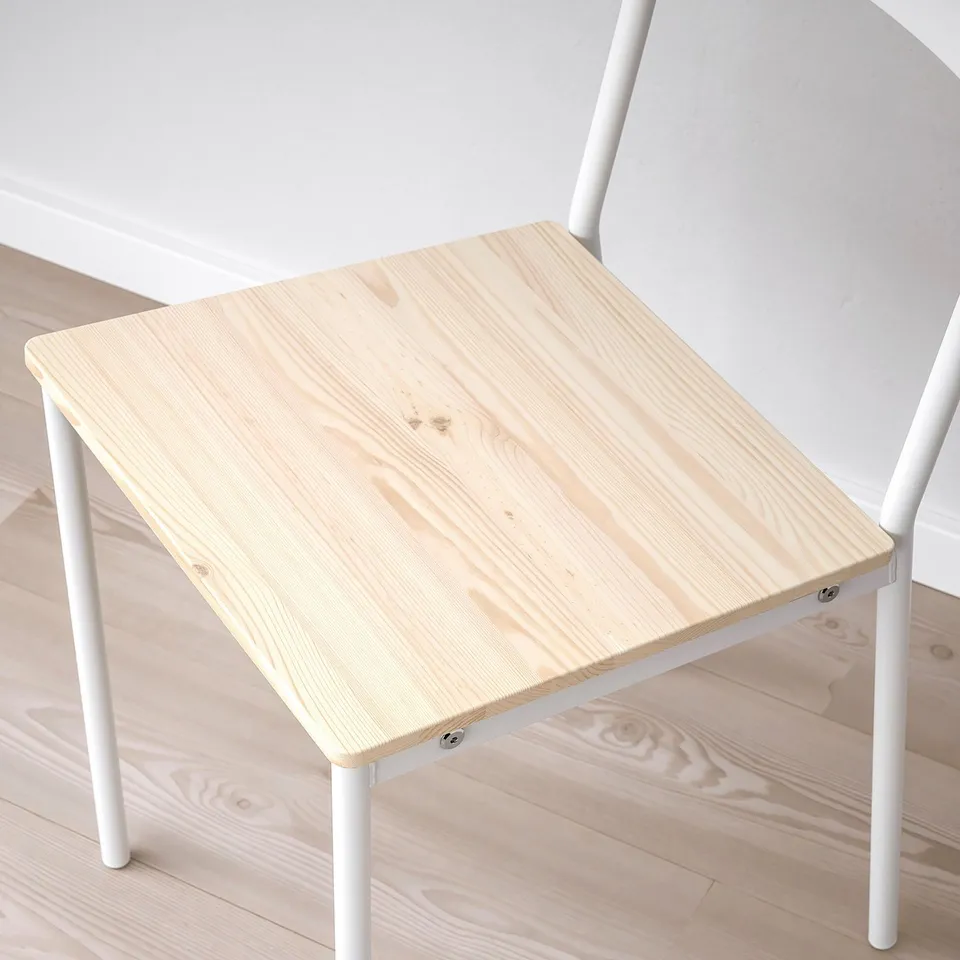Small, modern desk with light wood top and white metal legs, placed on light wooden floor next to white chair.