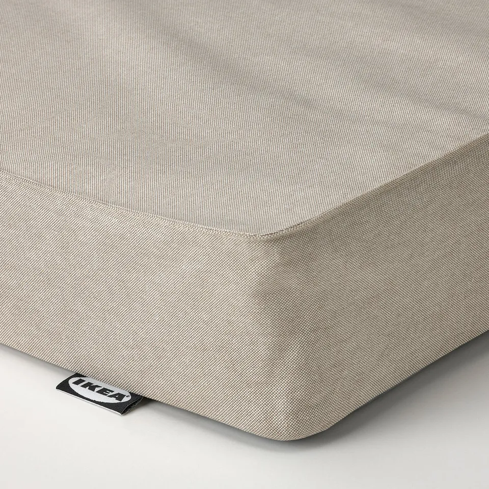 A close-up of a neatly made, high-quality mattress with a smooth, beige fabric cover. The stitching and material appear durable and well-crafted.