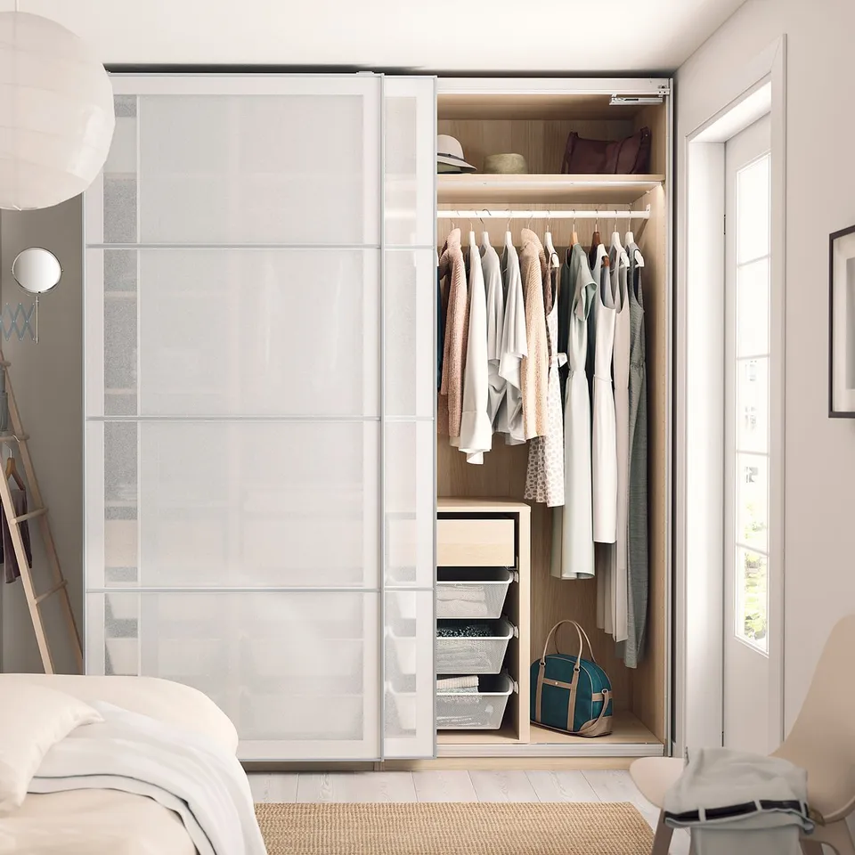 Modern bedroom with frosted glass SVARTISDAL wardrobe, clothes, mirror, and pendant light.
