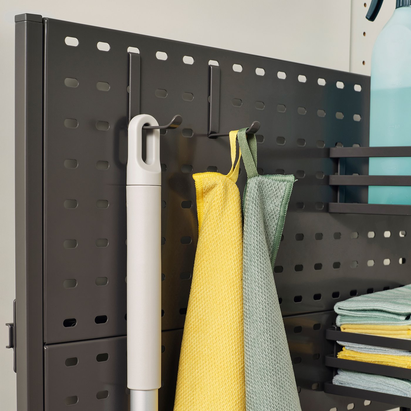 Black shelf with cleaning supplies: cloths, mop. Well-organized.