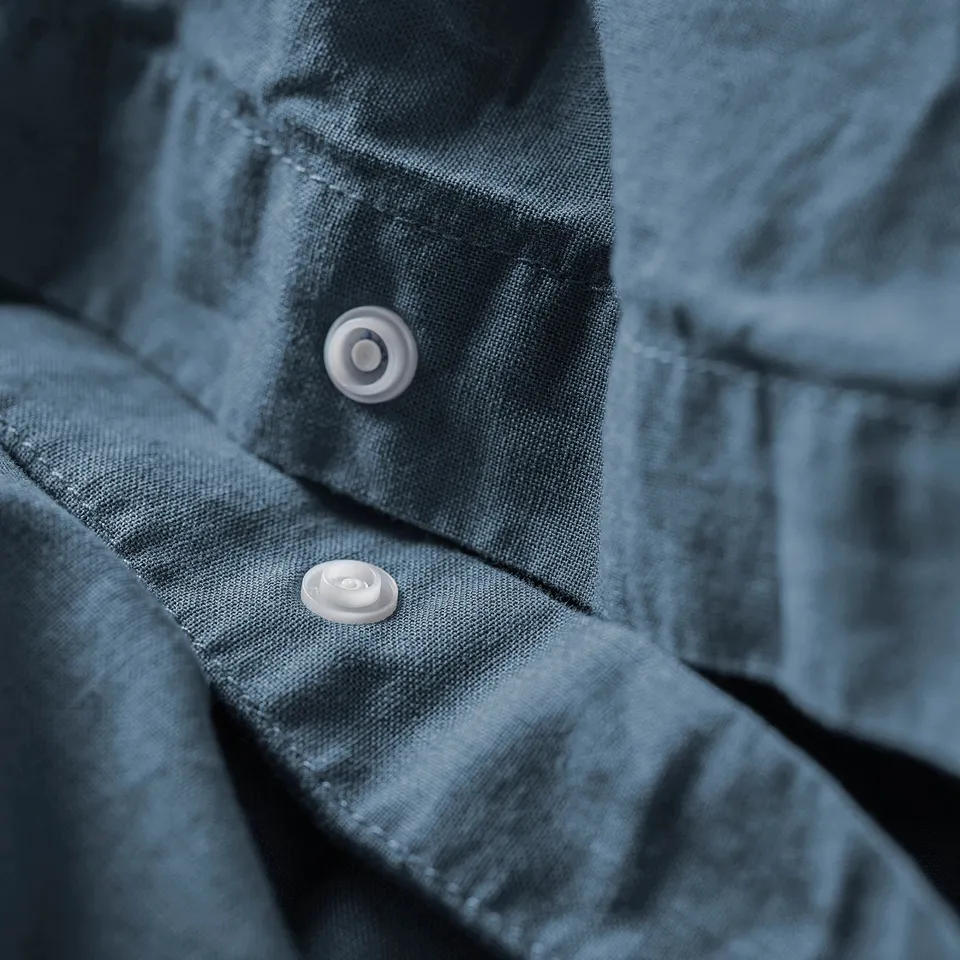 Close-up of light blue duvet cover with two visible white buttons. The fabric appears soft and textured.