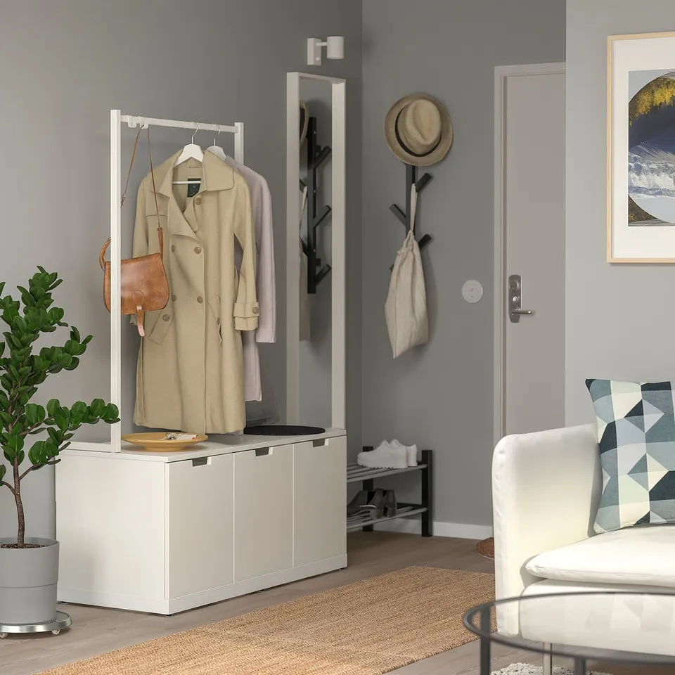 Minimalist entryway: NORDLI chest, coat, mirror, chair, plant.