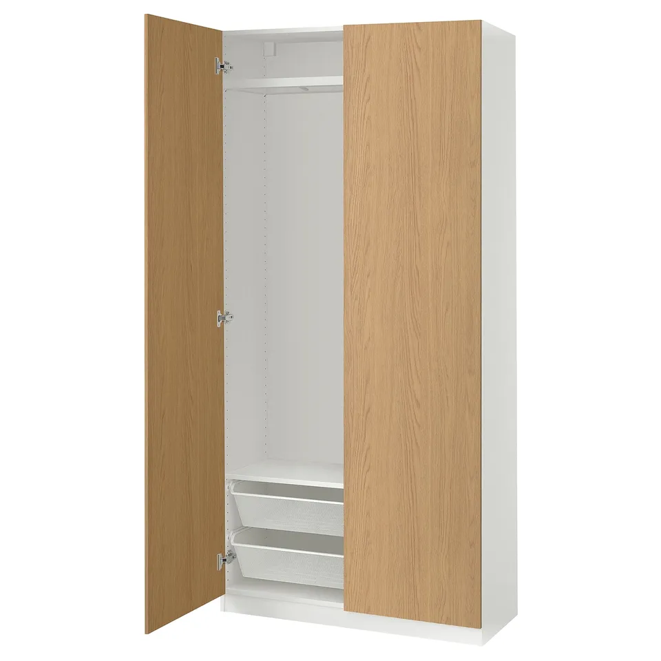 An IKEA PAX wardrobe in white and oak. It two open doors revealing an empty interior with shelves and a hanging rod.