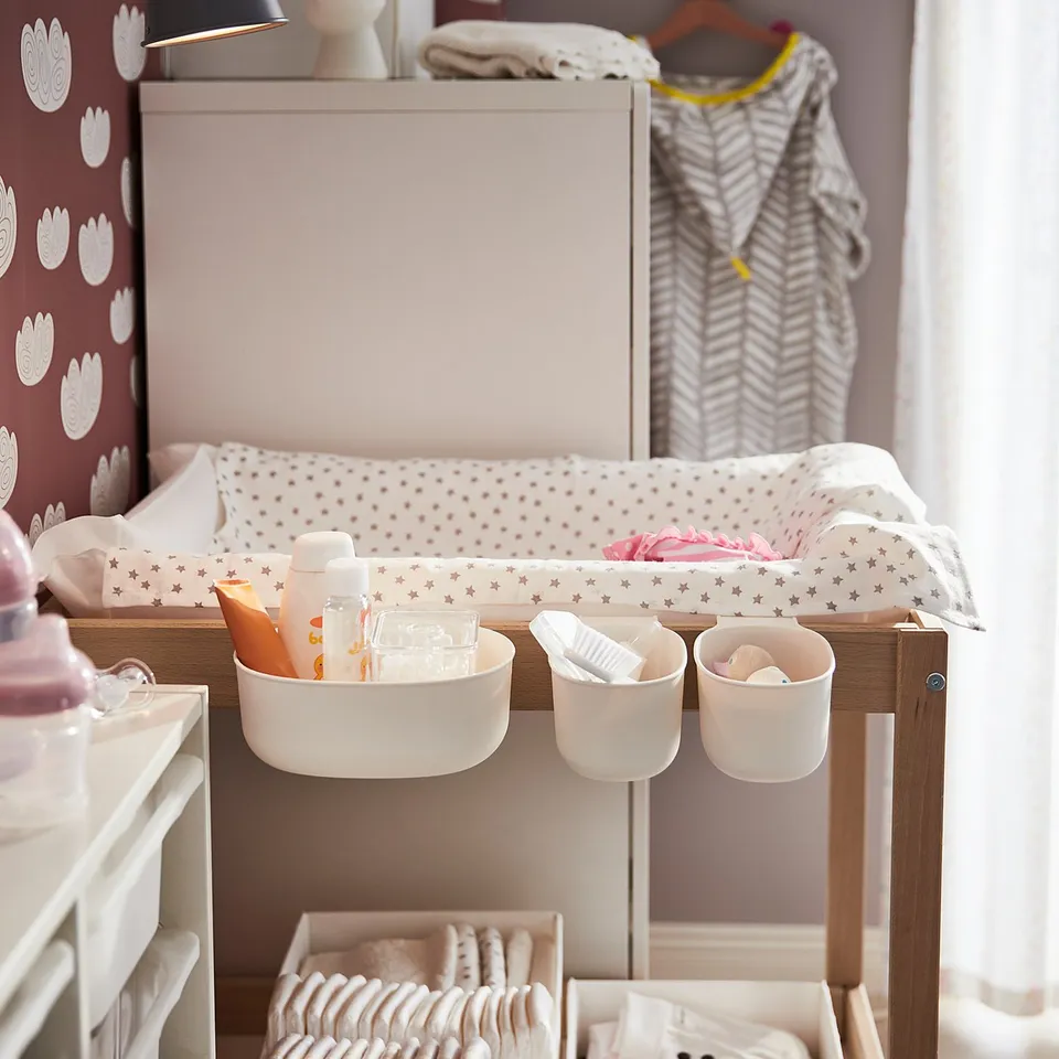 Changing station with white baskets and hooks holding baby items. Diapers and toiletries organised efficiently for easy access.