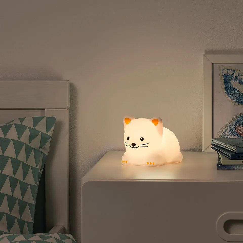 Cat-shaped night light on cabinet, white silicone, soft glow.