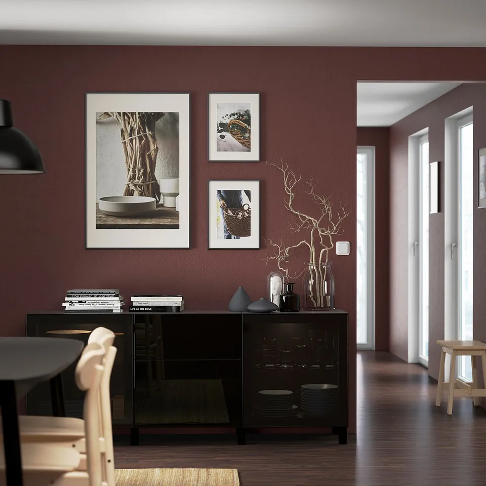 Modern dining area with black BESTÅ sideboard, glass doors, dishes, and art.