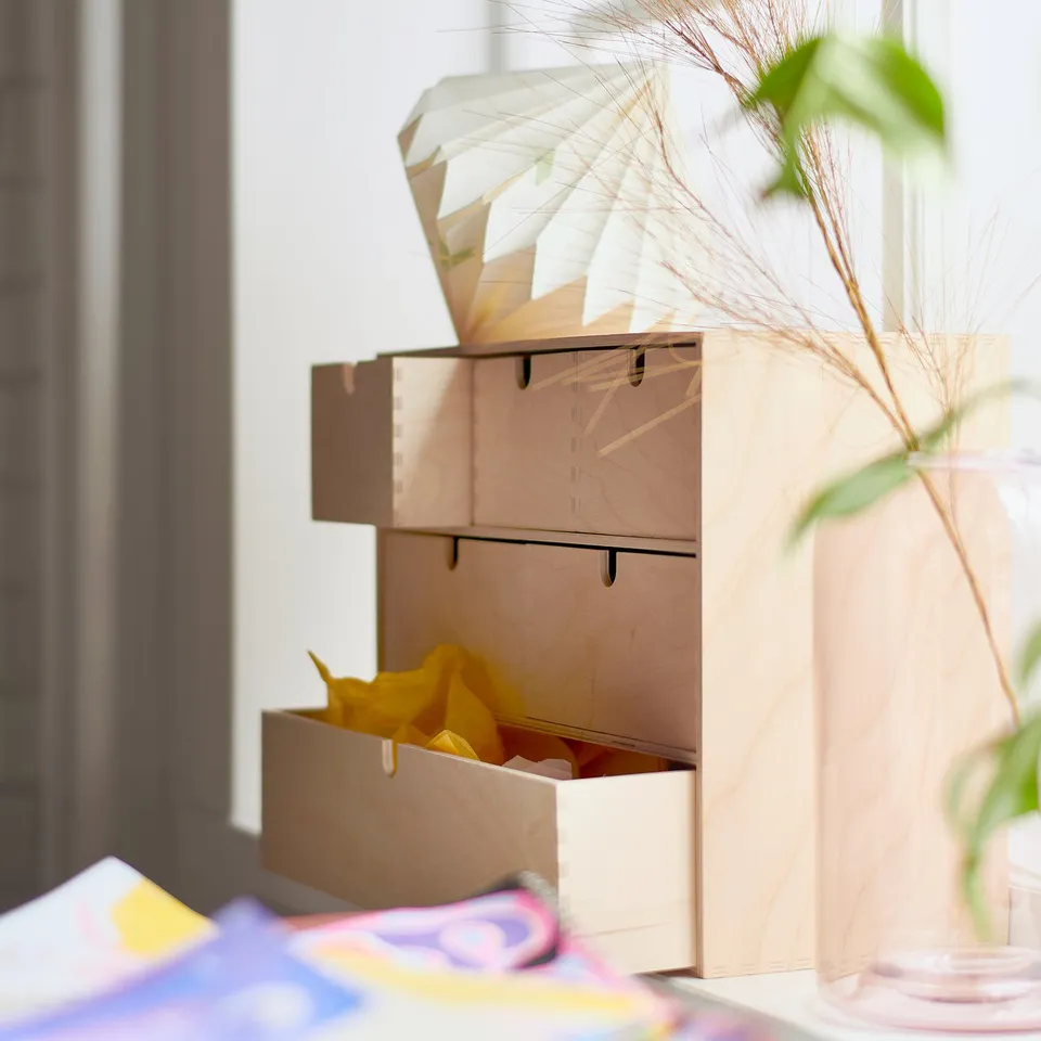Mini MOPPE wood storage unit with drawers, bright colour, near colourful books and plant.