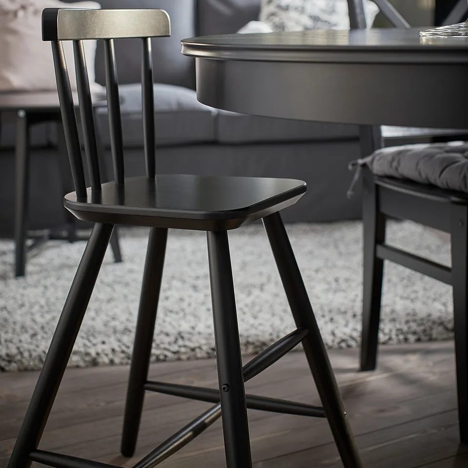 Black junior chair for kids at dining table, modern design, made of acrylic painted wood, supportive back and legs.