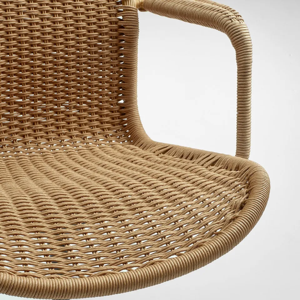 Handwoven wicker chair, close-up. Intricate texture, natural tone. Curved armrest and seat detail.
