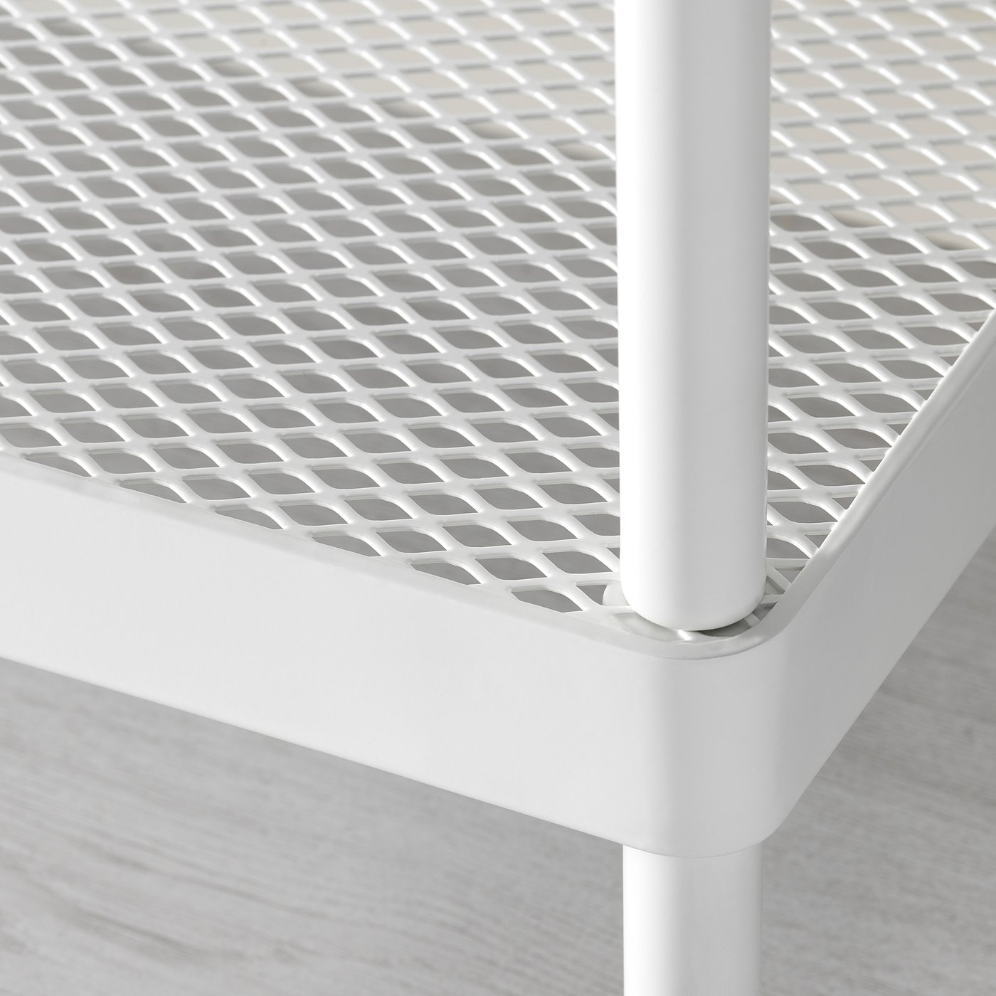 Close-up of durable, white metal shelf showing intricate mesh pattern and sturdy connexion.
