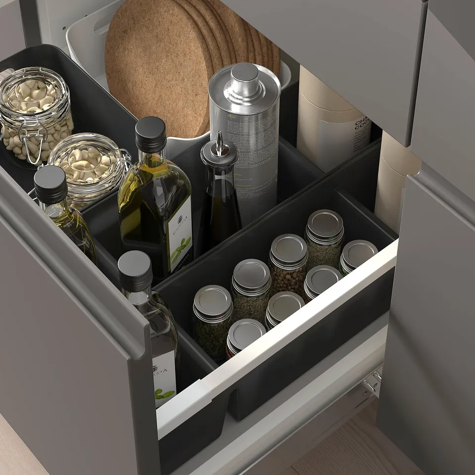 Kitchen drawer organiser holding bottles, jars, nuts, oils, spices, and cleaning supplies.