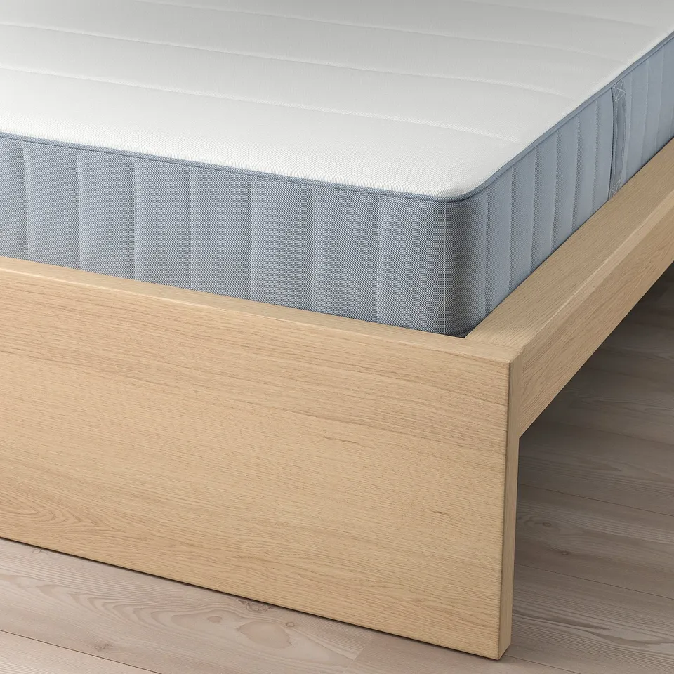Light wood-framed bed with a light grey mattress, jointly showcasing adjustable bed sides and slatted support.