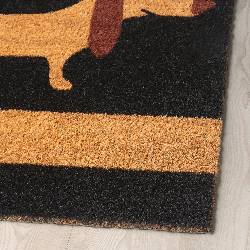 Doormat with striped pattern and dachshund design. High-quality coir material, thick and textured, laid on a wooden floor.