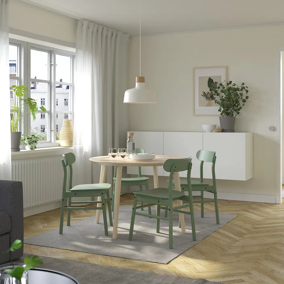 Modern dining area with LISABO table, four green chairs, window, pendant light, and grey rug.