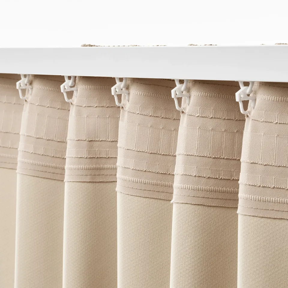 Beige room-darkening curtains with white hooks, blocking light and offering privacy.