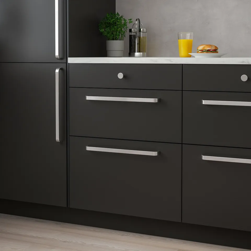 Modern kitchen with small, sleek, metallic KALERUM handles on dark cabinets, complementing a clean design with minimalistic aesthetics.