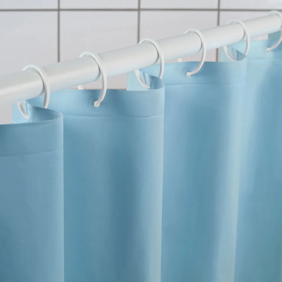 Light blue shower curtain hangs from white rod with hooks, displaying water-repelling surface.
