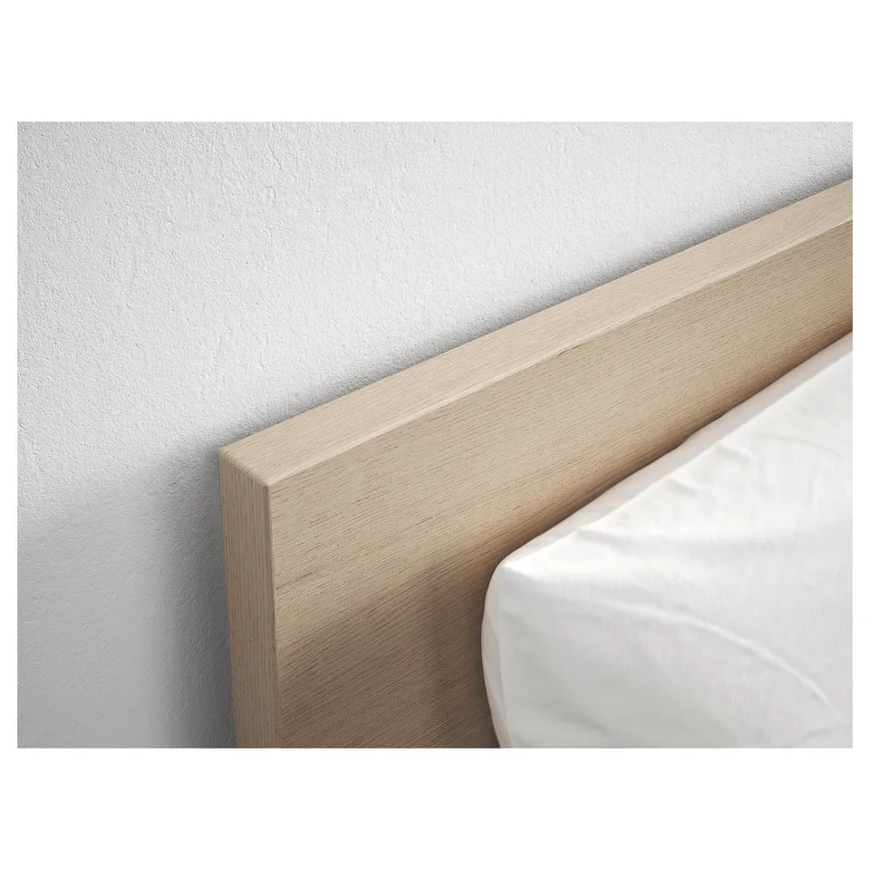 Light wooden headboard of a bed against a white wall, showcasing clean, modern design and sturdy construction.