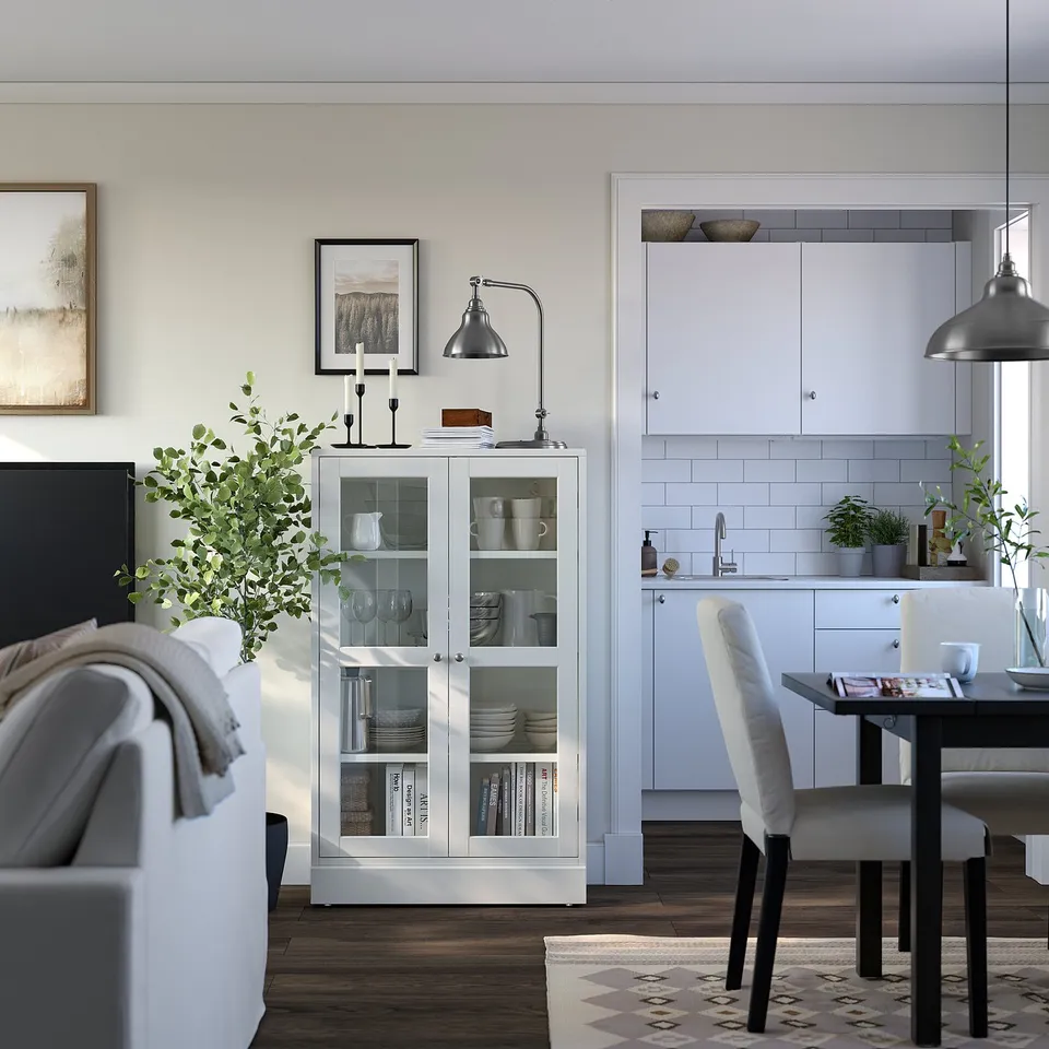 Modern living room with white HAVSTA cabinet, books, dining set, plants, art, grey sofa.