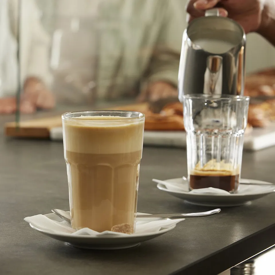 Two POKAL glasses with coffee, one being filled with foam.