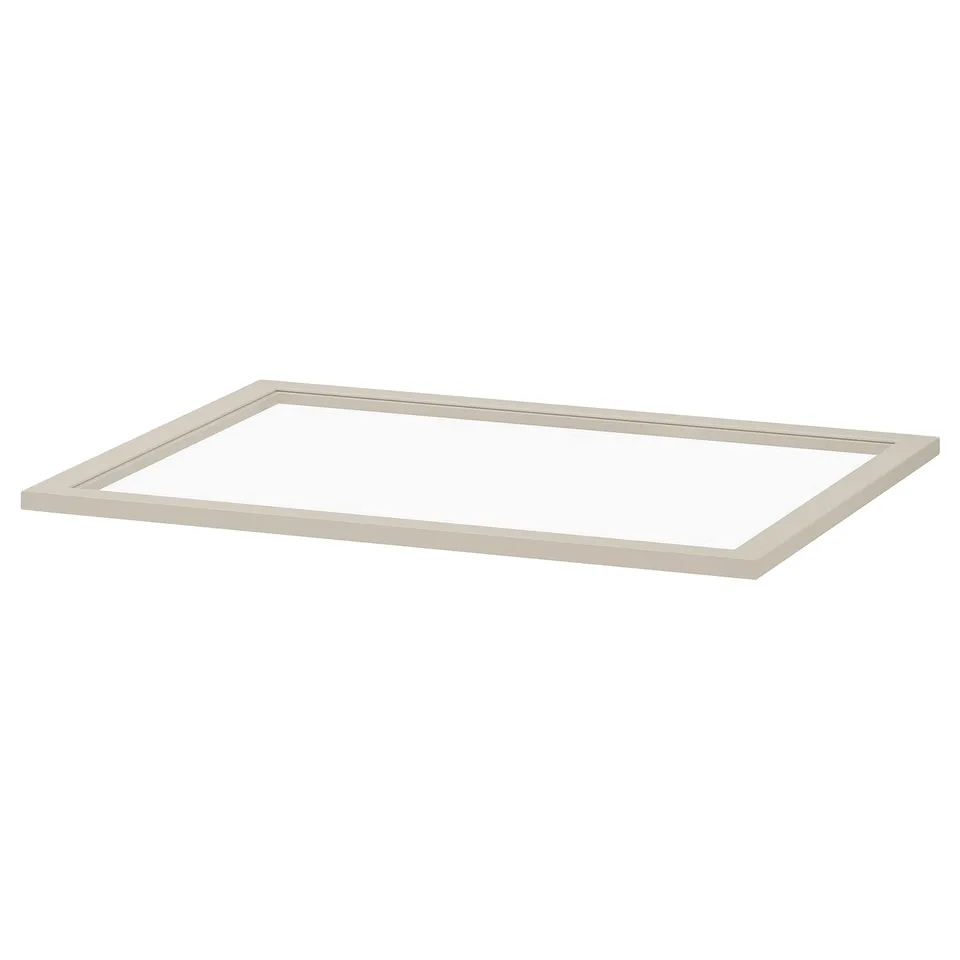 A KOMPLEMENT glass shelf in beige. Sleek, rectangular design, ideal for storing lighter clothes or displaying items within a cabinet.