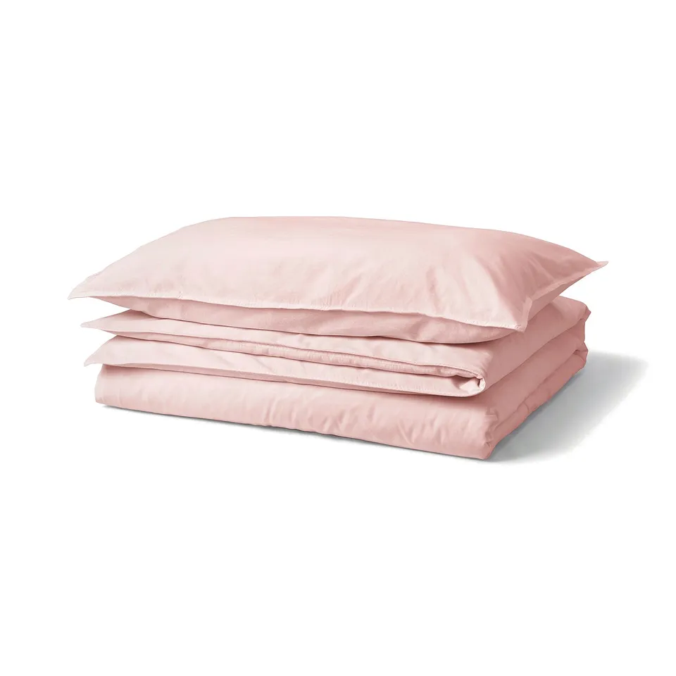 Pink folded duvet cover & pillowcases from IKEAs ÄNGSLILJA collection, made of recycled cotton.