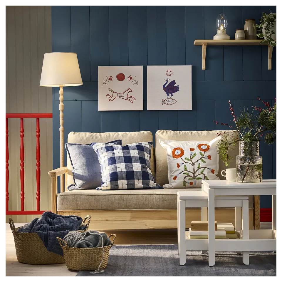 Blue living room with beige sofa, plaid cushions, red bench, wicker baskets, plant coffee table, wooden lamp, wall art.