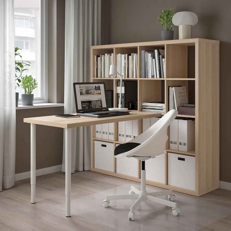 Modern home office with KALLAX bookshelf, desk, laptop, and plants.