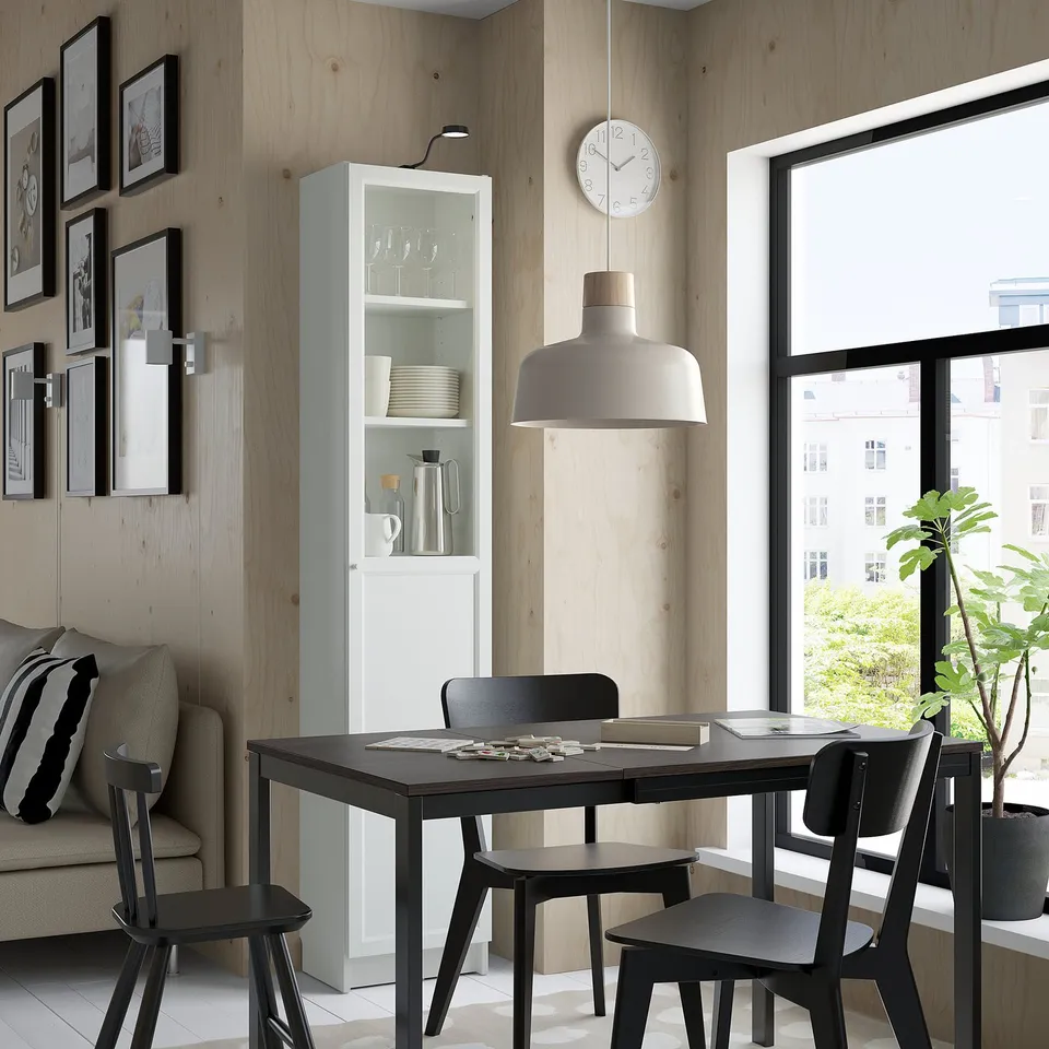 Modern dining area with BILLY white bookcase, black table, chairs, sofa, and a large window.