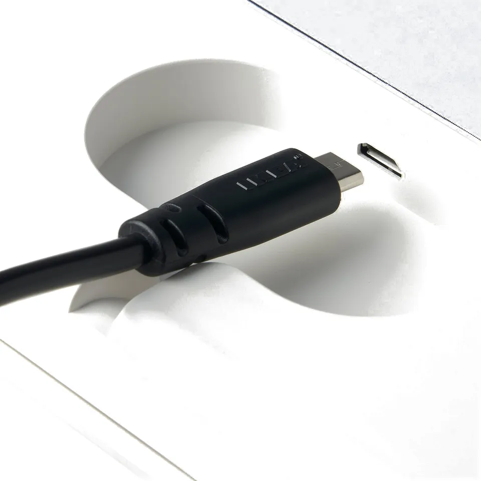 Black usb cable connected to white charging tray for PRAKTSPIREA battery-operated lamps.