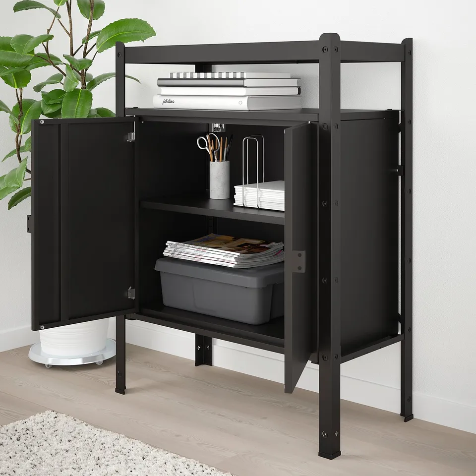 Black metal storage unit with open doors, holding office supplies like books, papers, and containers. Sturdy, robust design suitable for heavy loads.