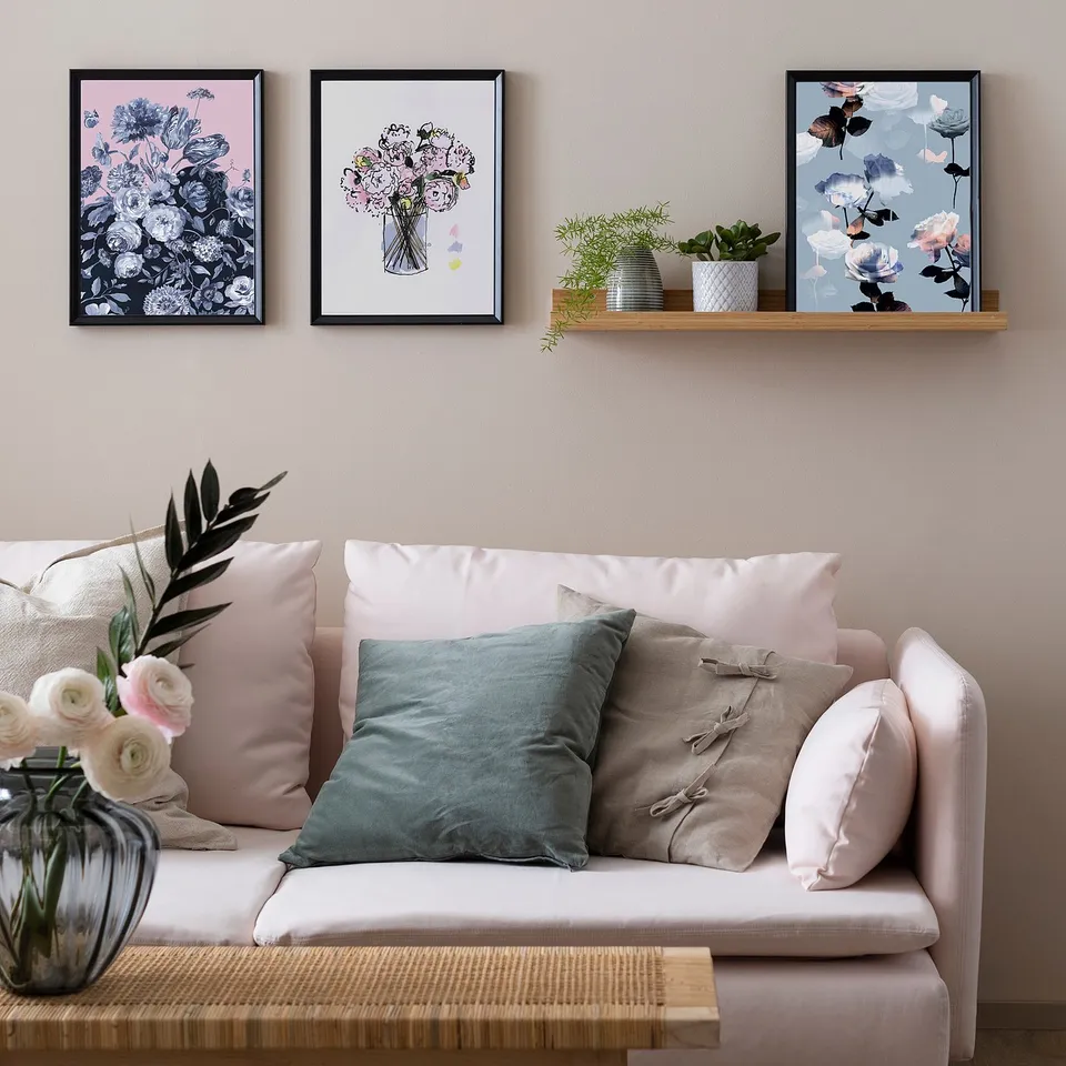 Cosy living room with white couch, colourful pillows, floral art, plants, and pastel decor.