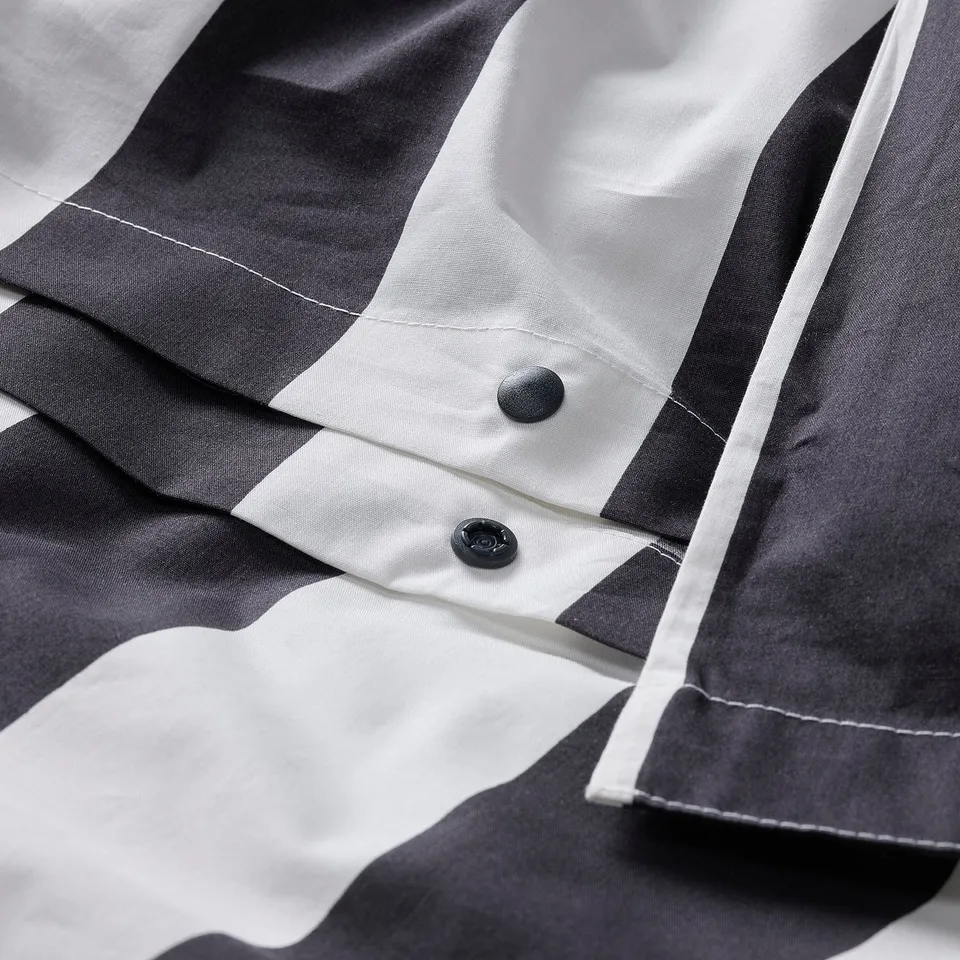 Close-up of a grey and white striped duvet cover with button closure.