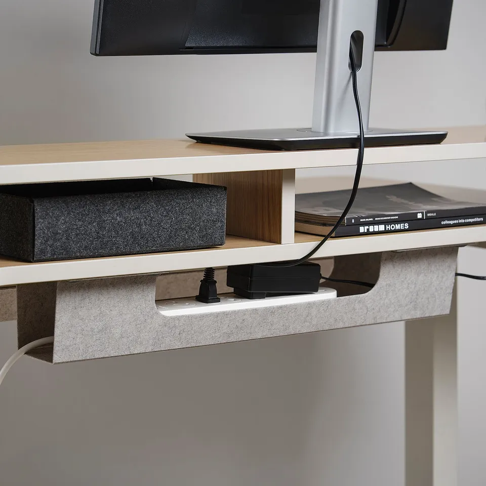 Desk shows cable management: wires run through undershelf slots.