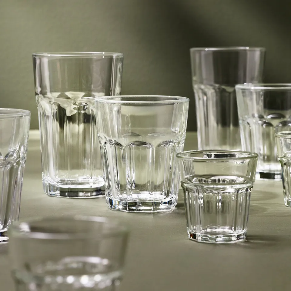 Collection of clear POKAL glasses in various sizes on green table.