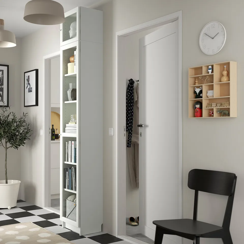 Modern hallway with BILLY bookcase, decor, black chair, chequered floor, and wall clock.